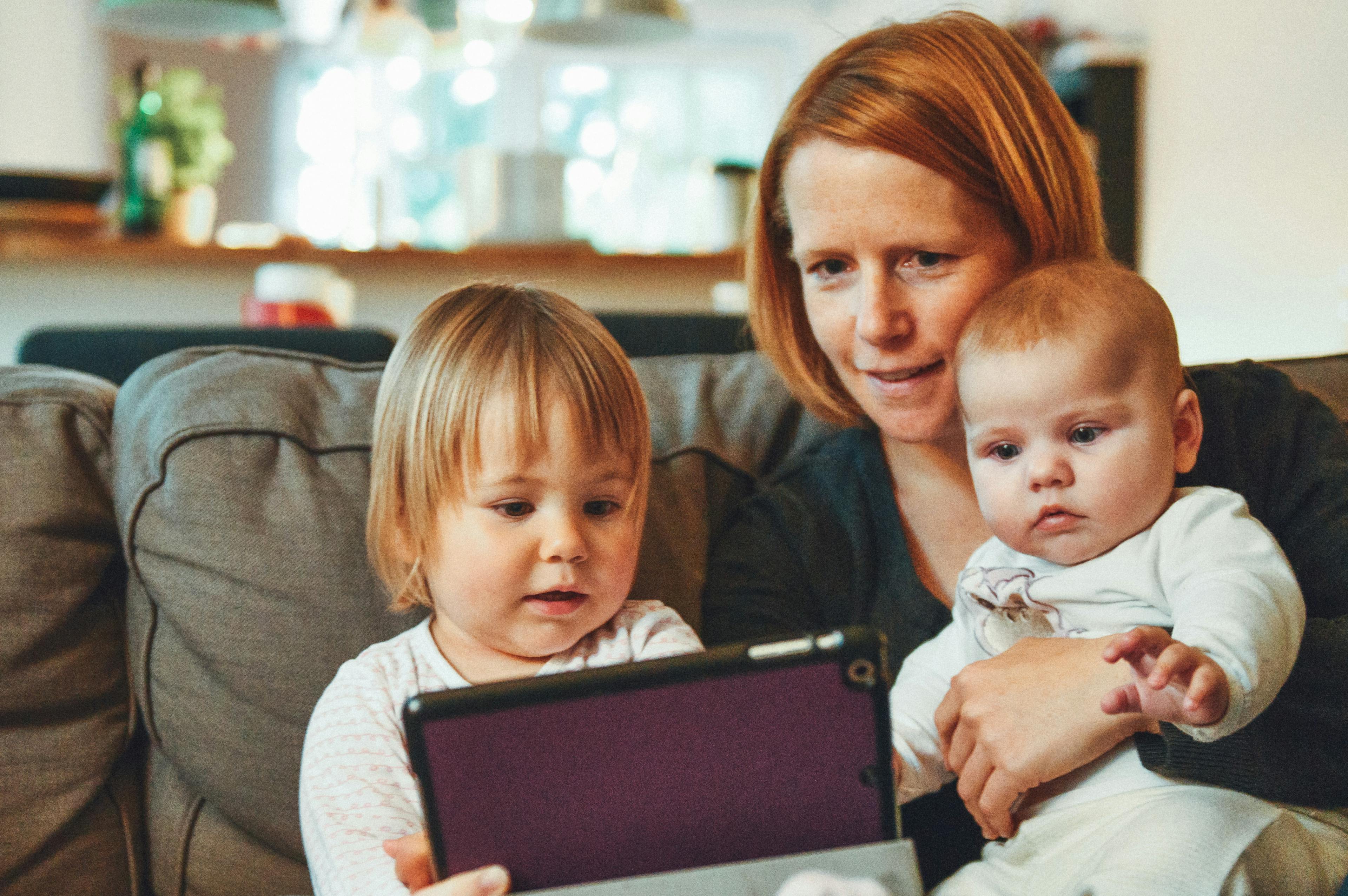 A mother and her two young children using a tablet together